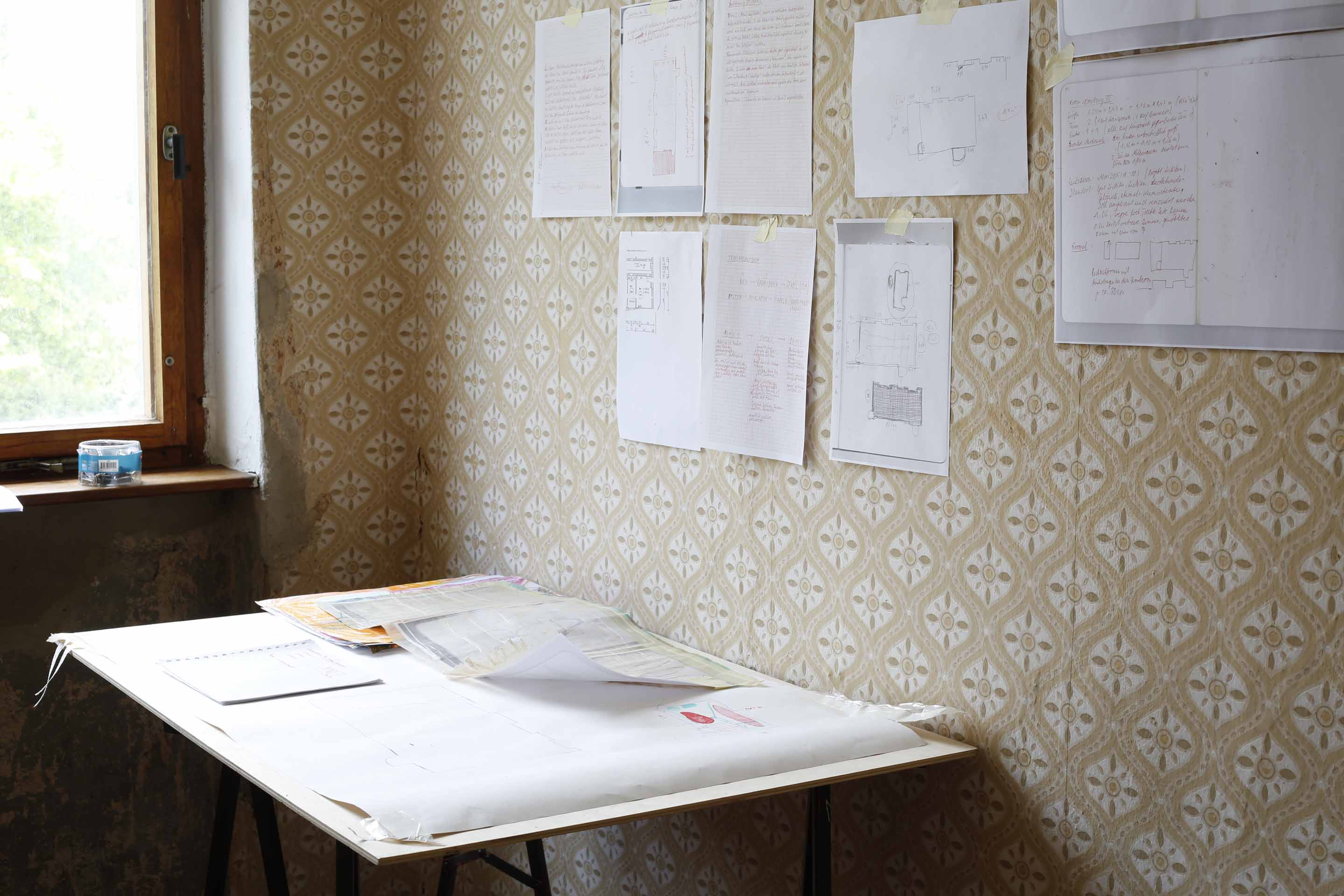 installation view - investigative setting with drawings on the wall and various notations and books on a table